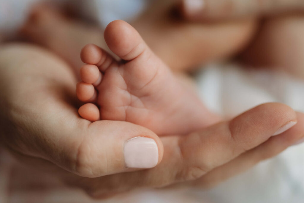 newborn baby toes being held by mother