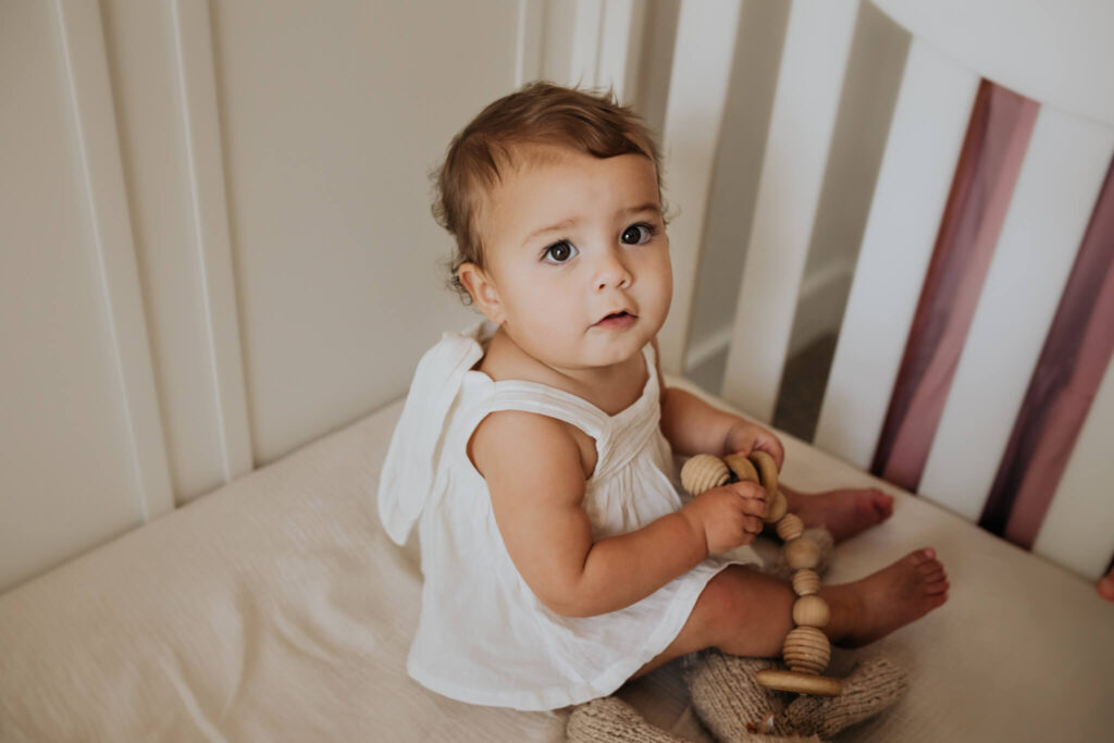 one year old girl sitting in crib