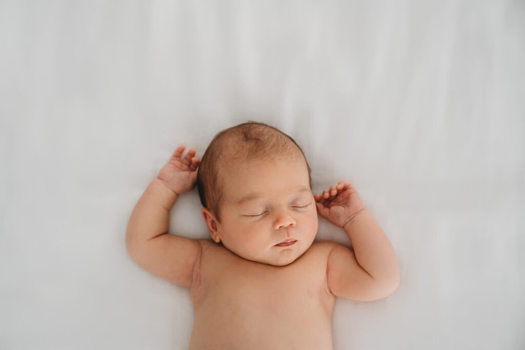 Baby asleep on a white sheet during her newborn photos