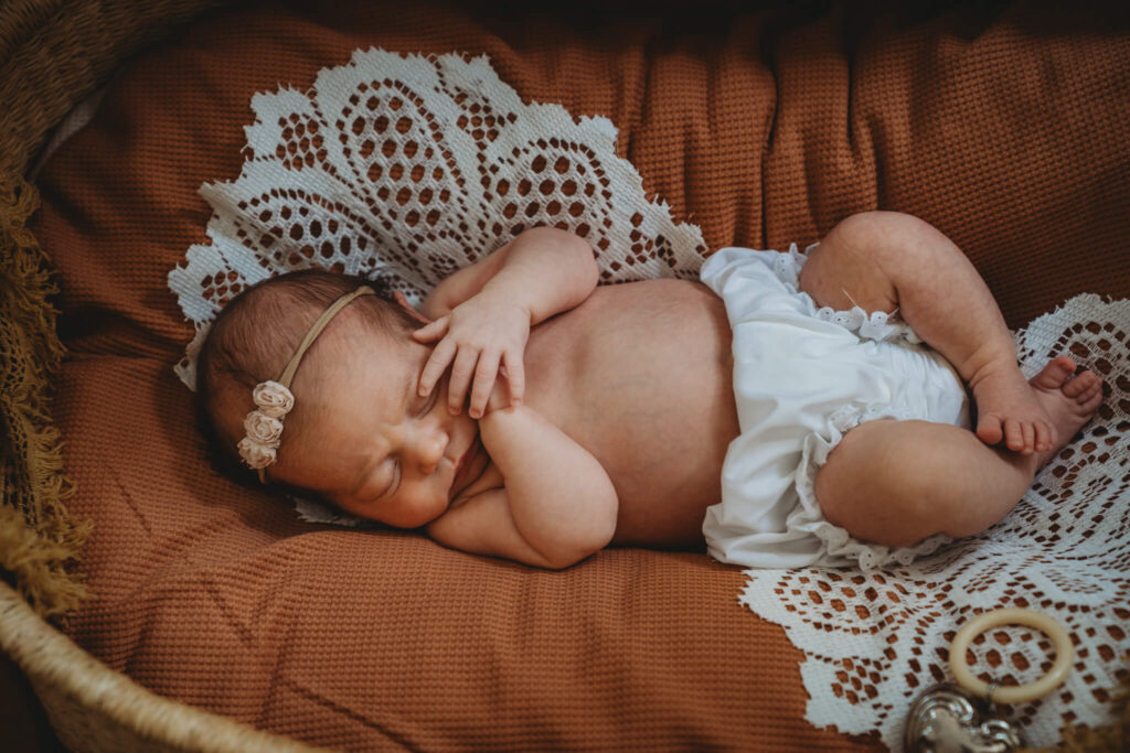 newborn baby in bloomers in a bassinet during her newborn photos in home