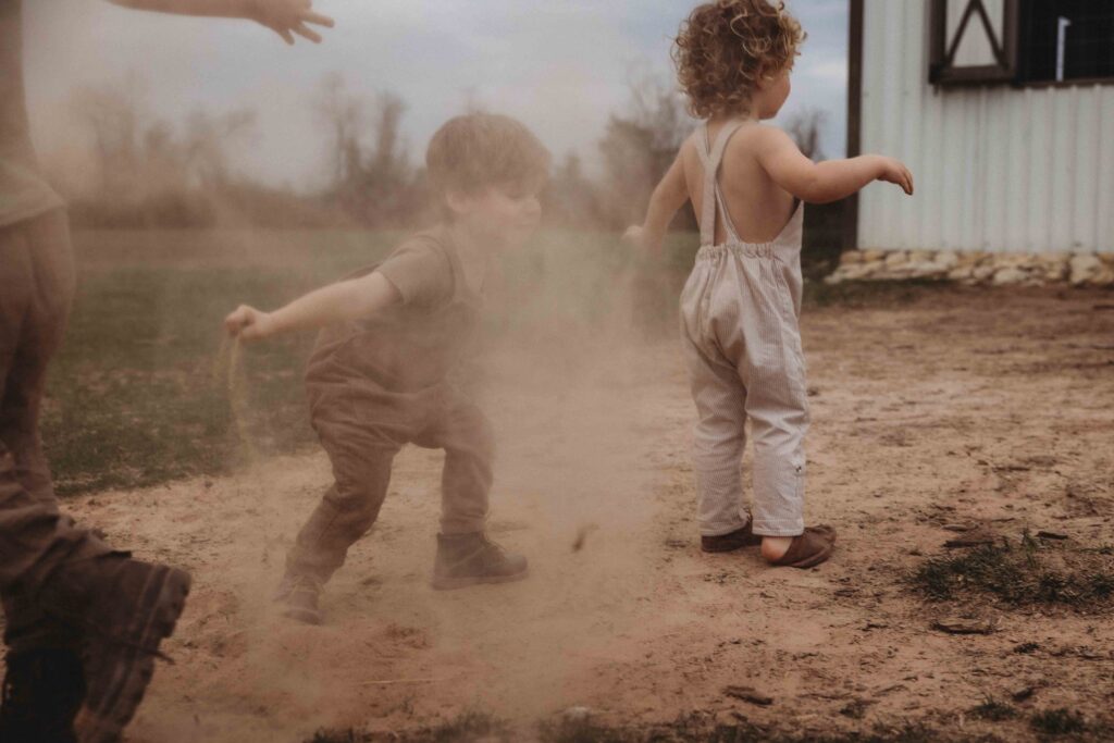 kids playing with dirt, throwing it in the air. family photo sessions are full of unfiltered moments