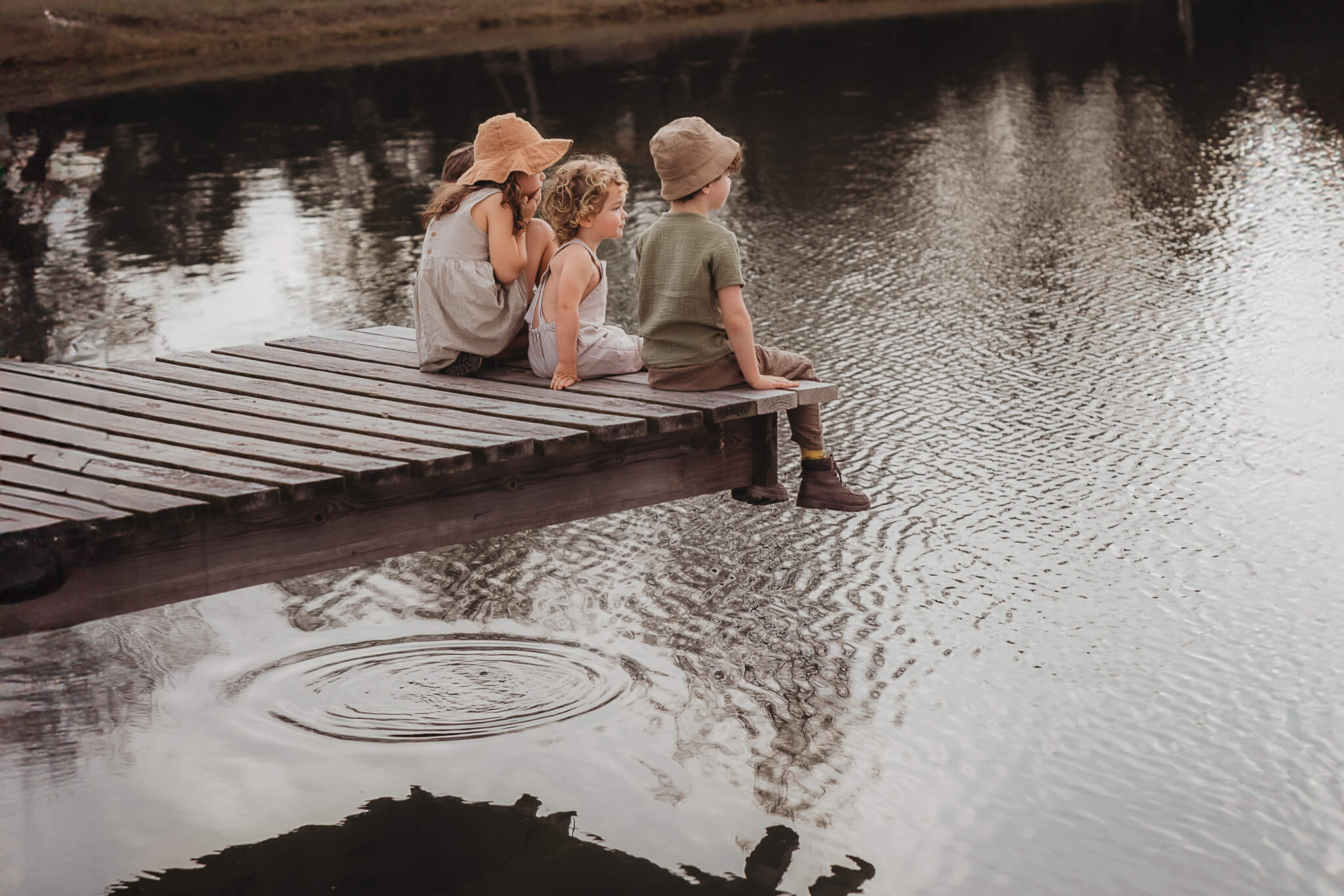 kids sitting on a dock wearing hats, the perfect accessory for a photoshoot 