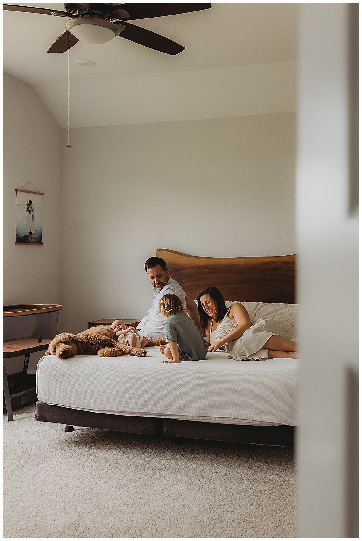 Family sit on the bed together showing Why You Should Choose An In-Home Newborn Session 