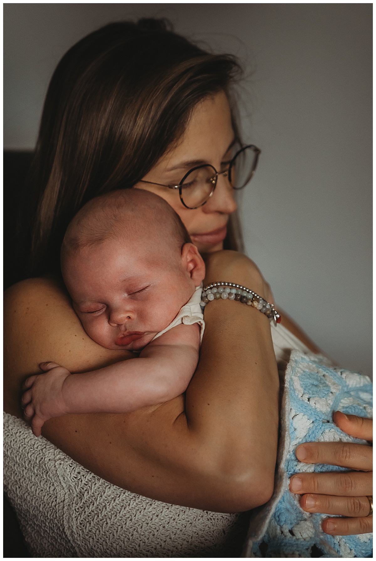 Mom cuddles young baby showing Why You Should Choose An In-Home Newborn Session 