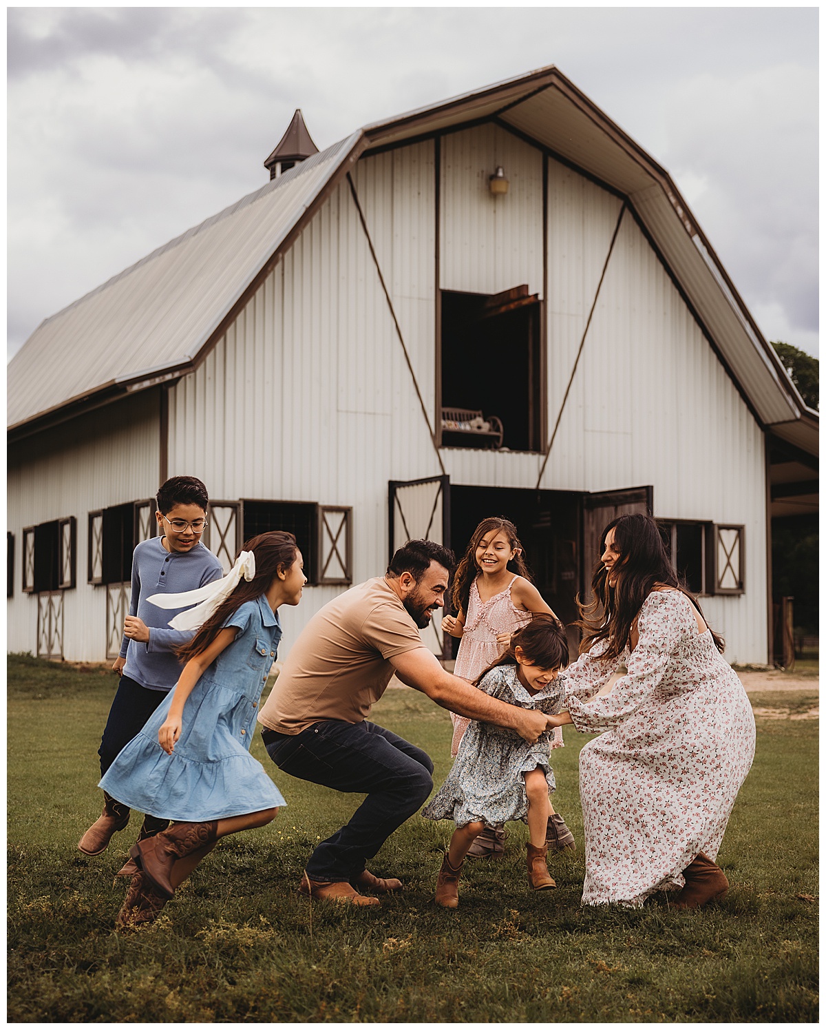 Family play together in front of of a barn during their Lifestyle Photography session