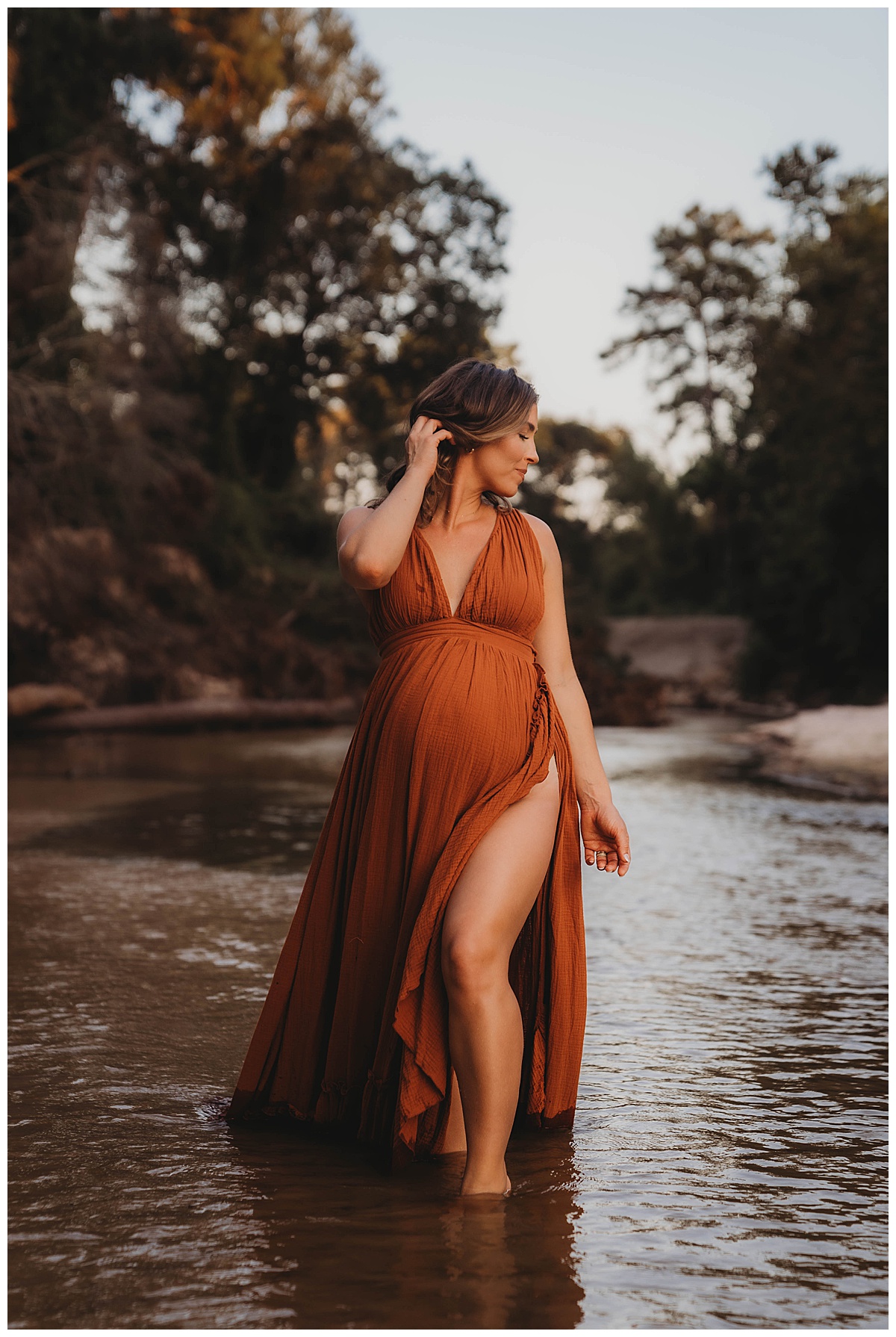 Female dances in the water showing off her baby bump by The Woodlands Family Photographer