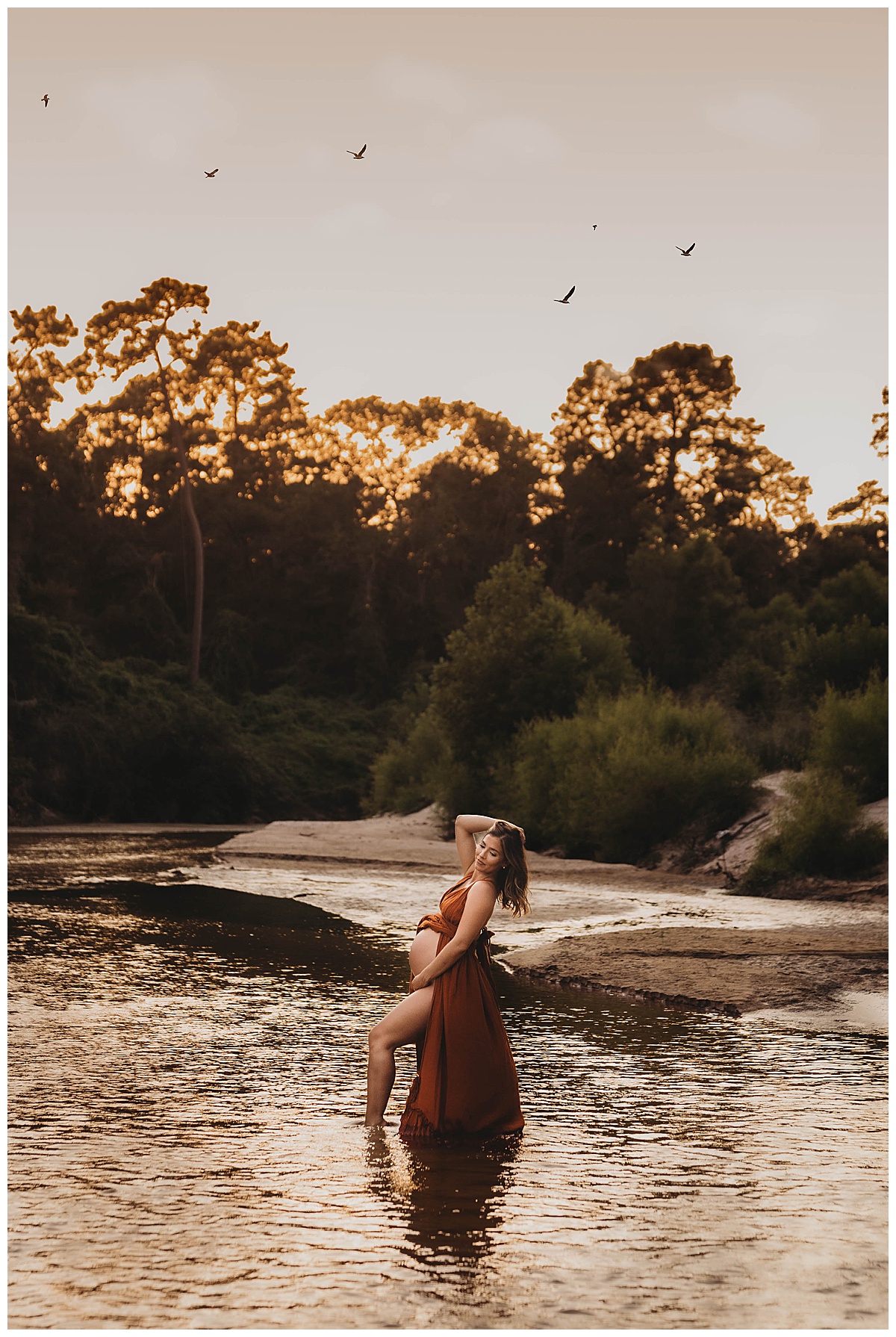 Adult stands in the water embracing her pregnant belly by by Maria Grace Photos