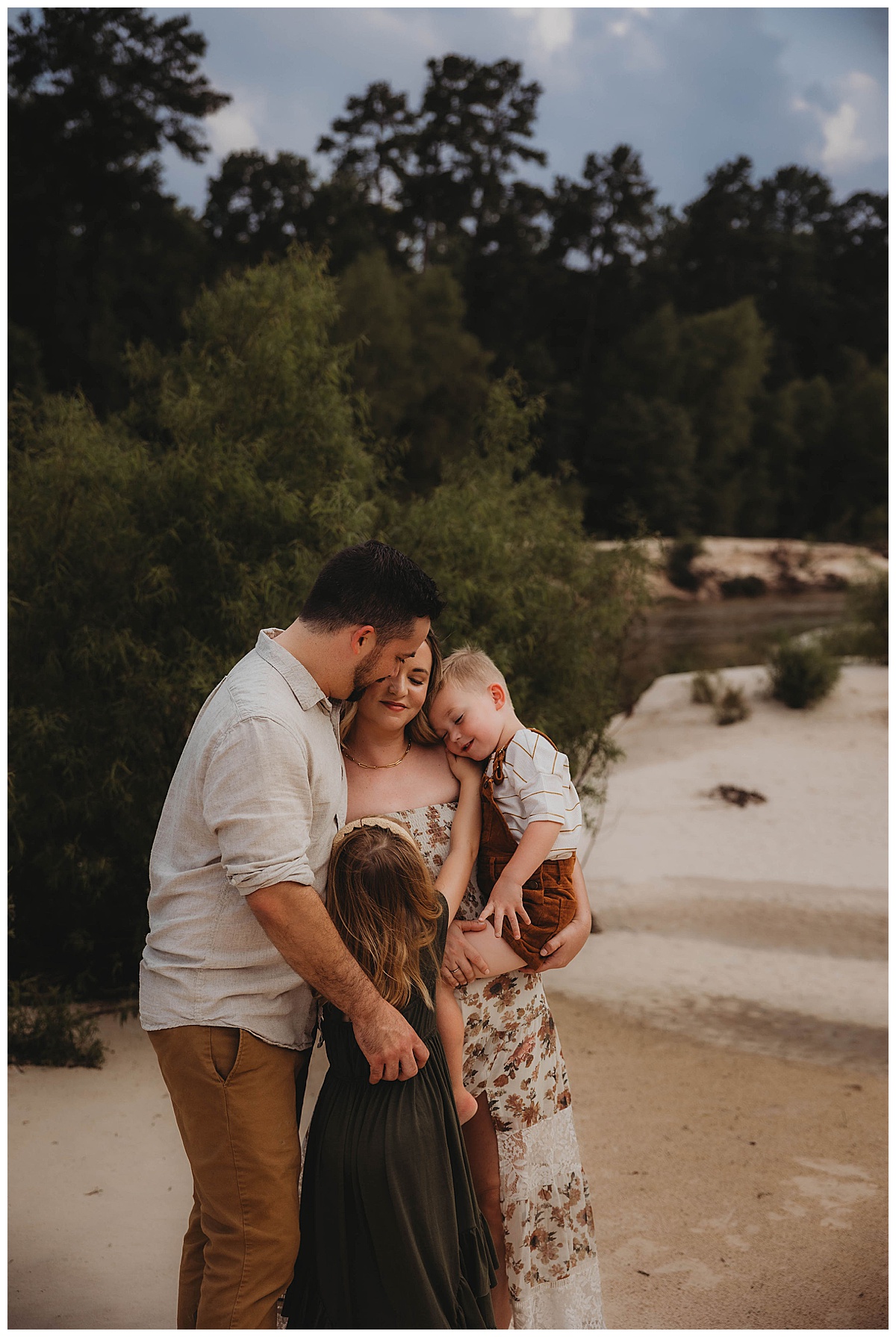 Family cuddle in close together by The Woodlands Family Photographer