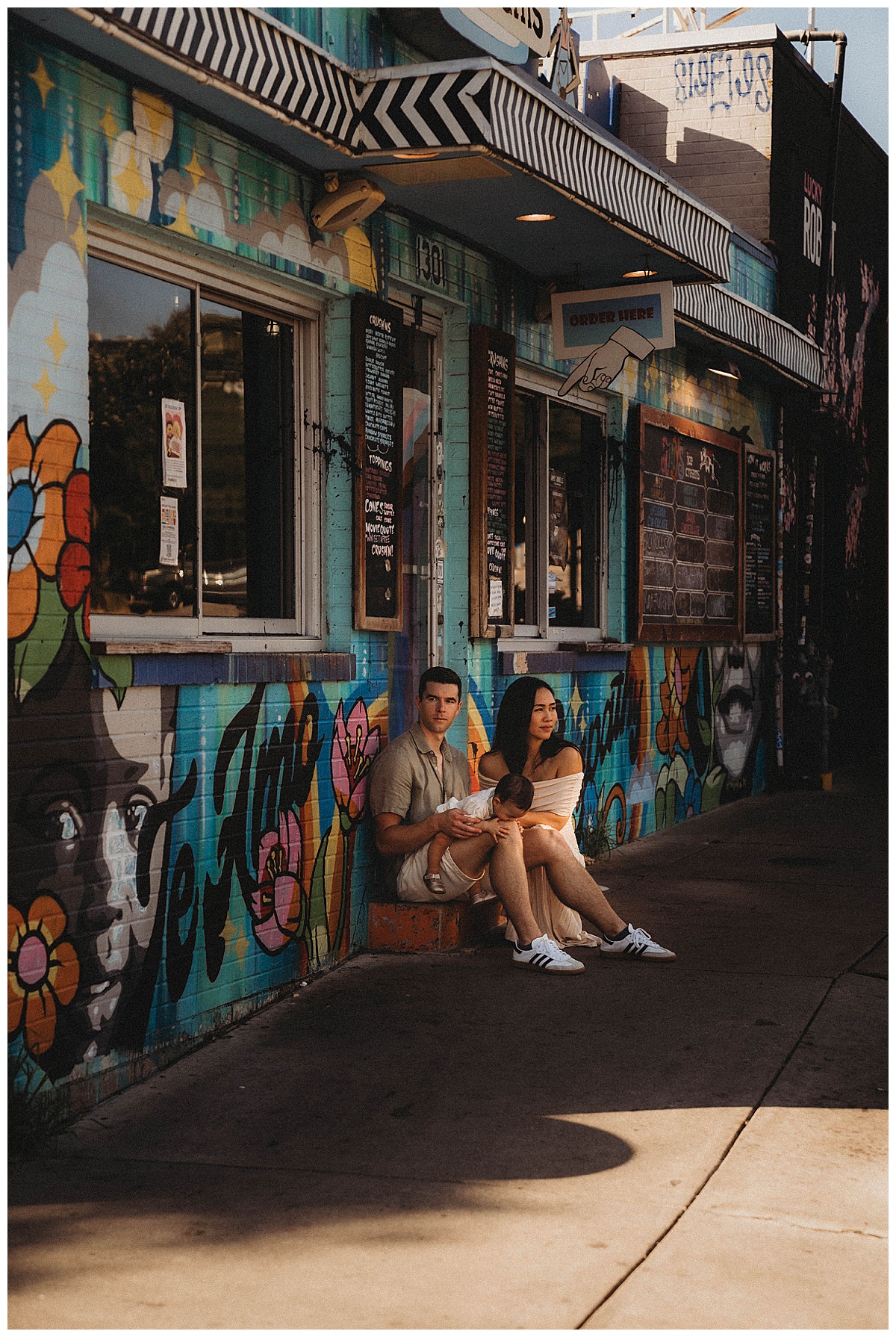 Parents sit against a graffiti wall for Maria Grace Photos