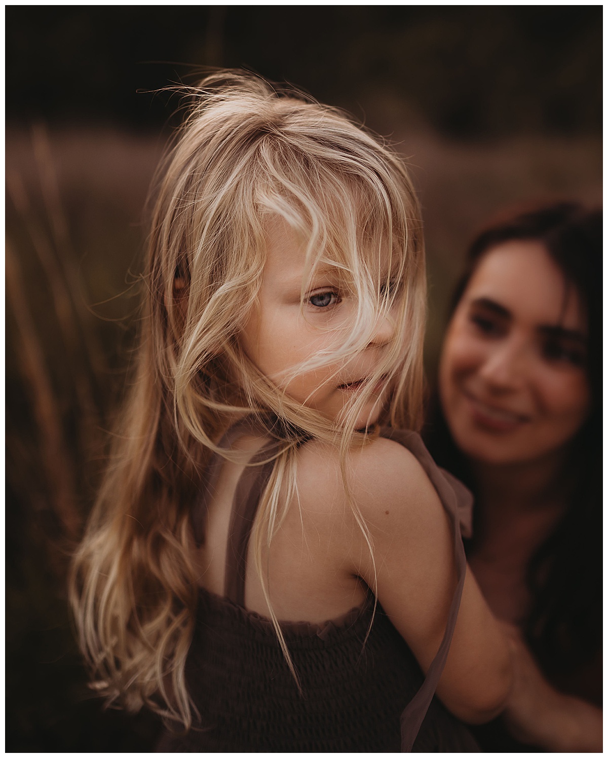 Young girl has her hair blowing hin her face forThe Woodlands Family Photographer