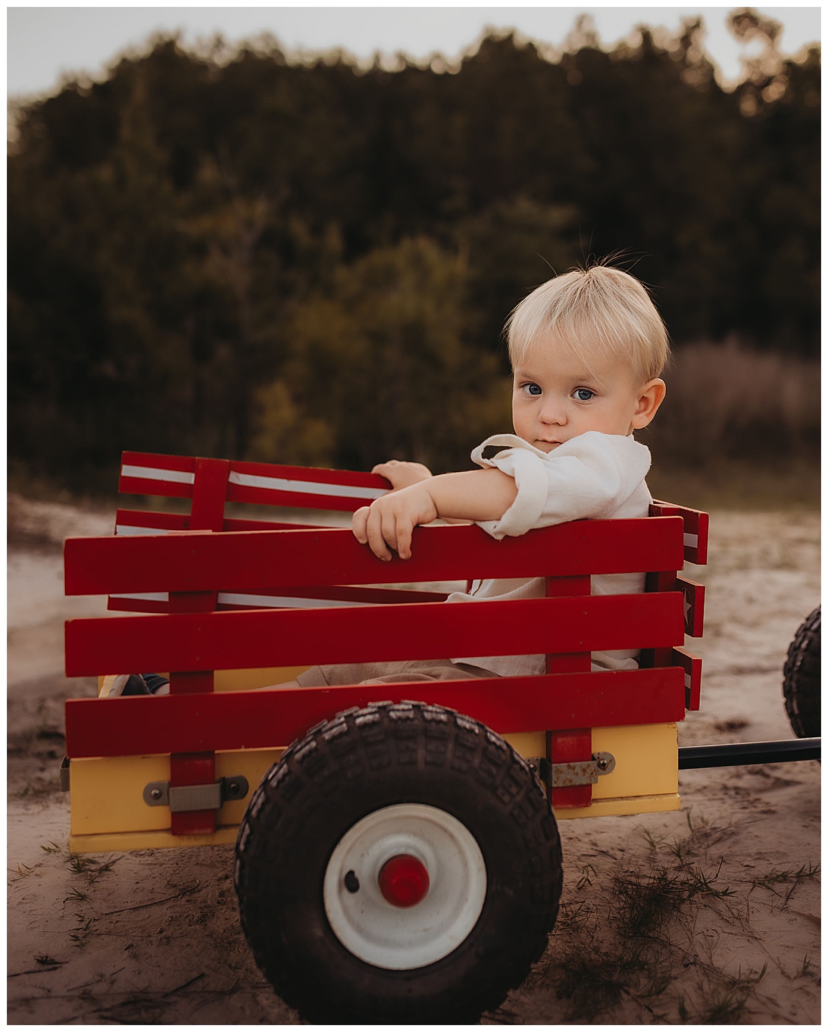 Young boy rides in a red wagon for The Woodlands Family Photographer