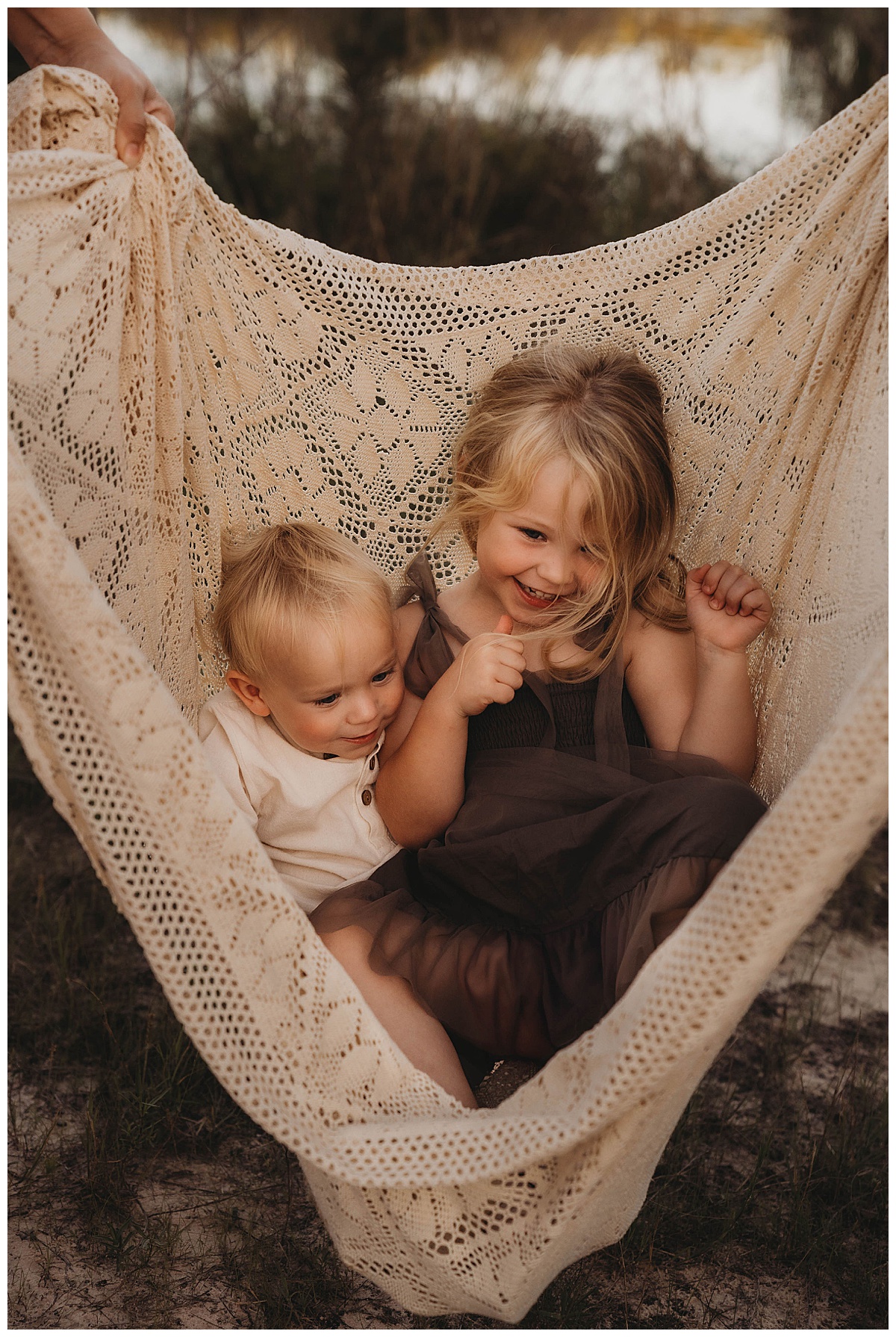 Kids laugh together while sitting in a blanket following my suggestion of Golden Hour for Family Photos