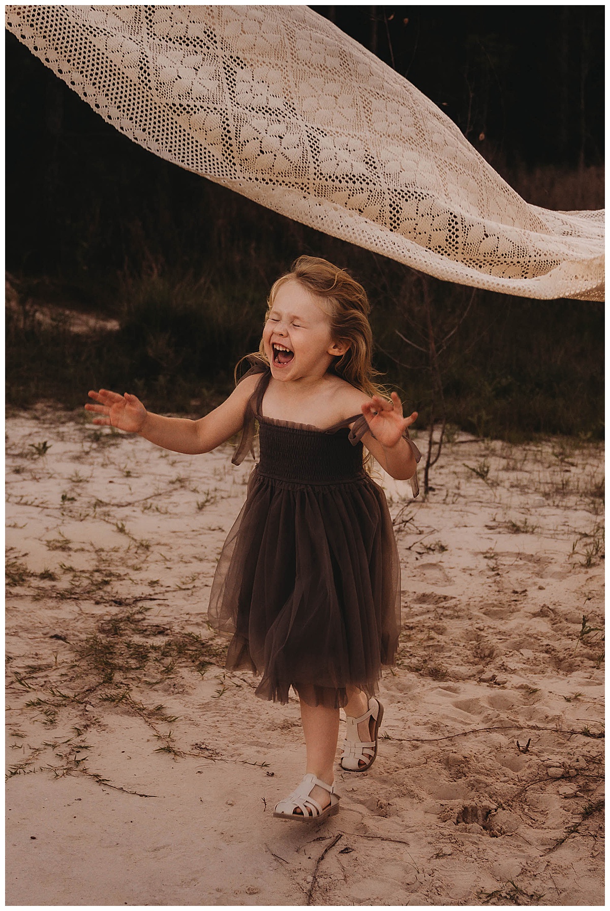 Young girl runs under the blanket for The Woodlands Family Photographer