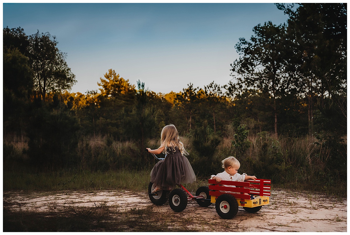 Older sister pulls brother in the wagon for The Woodlands Family Photographer