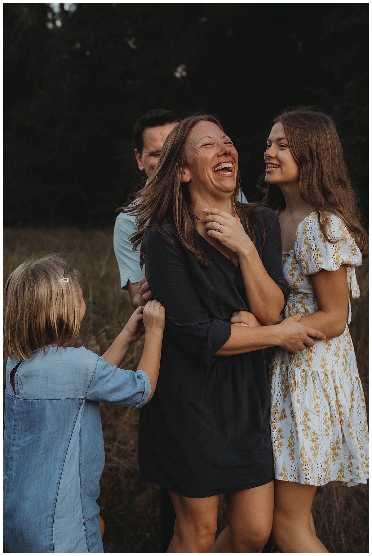 Mom smiles big surrounded by her family showing the importance of Printing Your Family Photos 